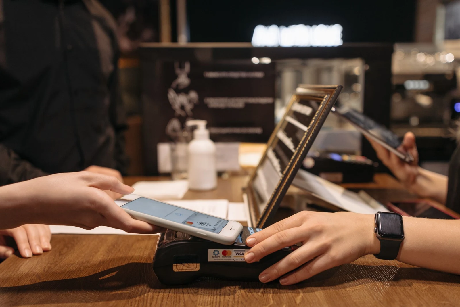顧客以手機在咖啡店付款終端進行感應支付的情境
